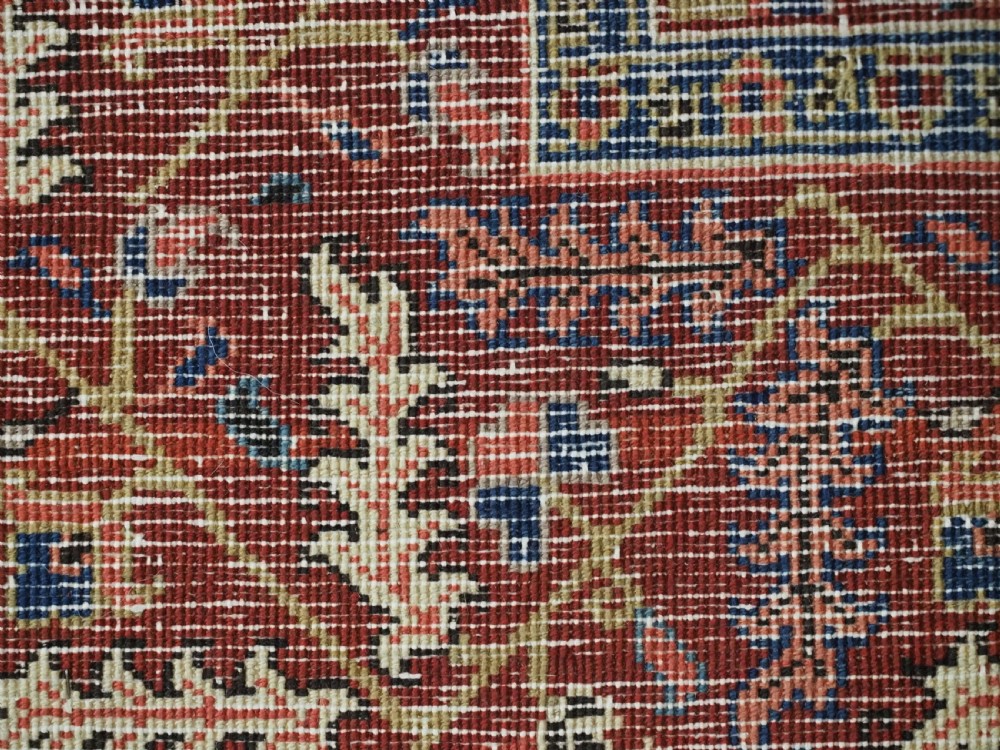 An antique hand-knotted Persian Heriz wool rug featuring a central eight-pointed red star medallion on an ivory ground with a detailed geometric red border. View XIV