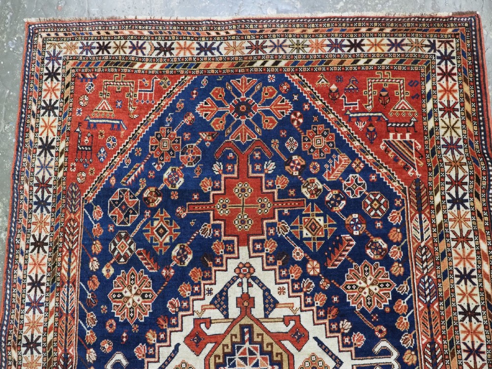 An antique hand-knotted Qashqai tribal rug featuring a central stepped diamond medallion in navy blue, red, and ivory surrounded by geometric peacock figures. View III