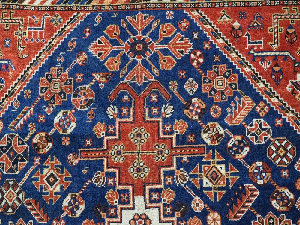 An antique hand-knotted Qashqai tribal rug featuring a central stepped diamond medallion in navy blue, red, and ivory surrounded by geometric peacock figures. View VIII