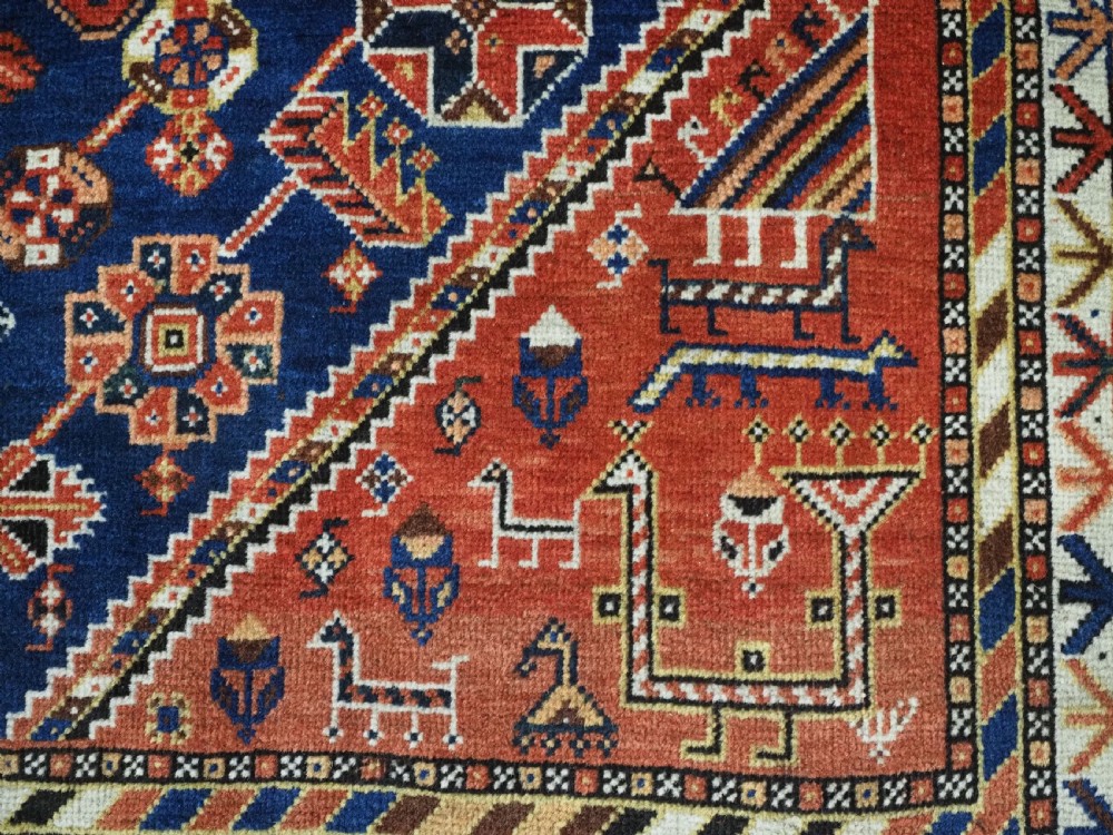 An antique hand-knotted Qashqai tribal rug featuring a central stepped diamond medallion in navy blue, red, and ivory surrounded by geometric peacock figures. View XI
