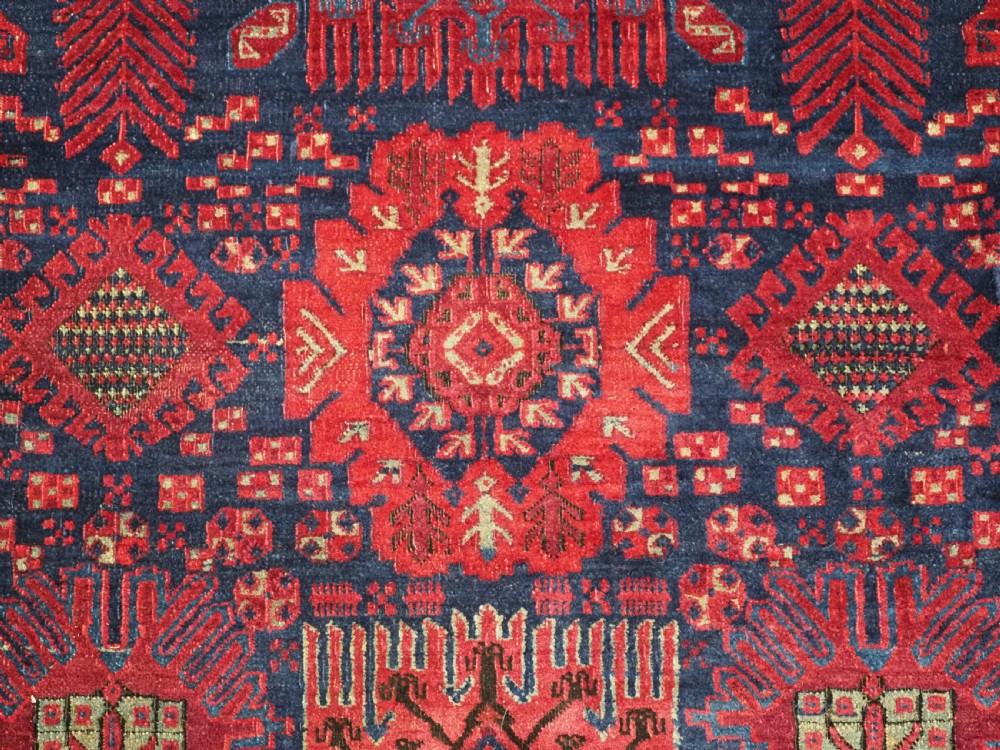 A large hand-knotted wool carpet featuring a repeating geometric medallion pattern in shades of crimson red, deep blue, and magenta. View XVIII
