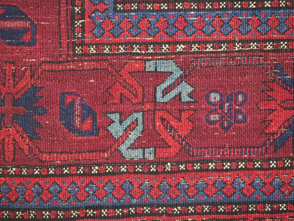 A large hand-knotted wool carpet featuring a repeating geometric medallion pattern in shades of crimson red, deep blue, and magenta. View XIX