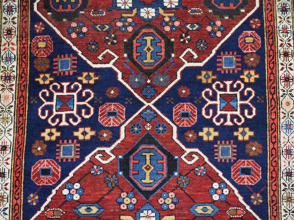 An antique hand-knotted Caucasian Alpan-Kuba runner rug featuring geometric diamond medallions in red and navy blue with detailed ivory borders. View XII