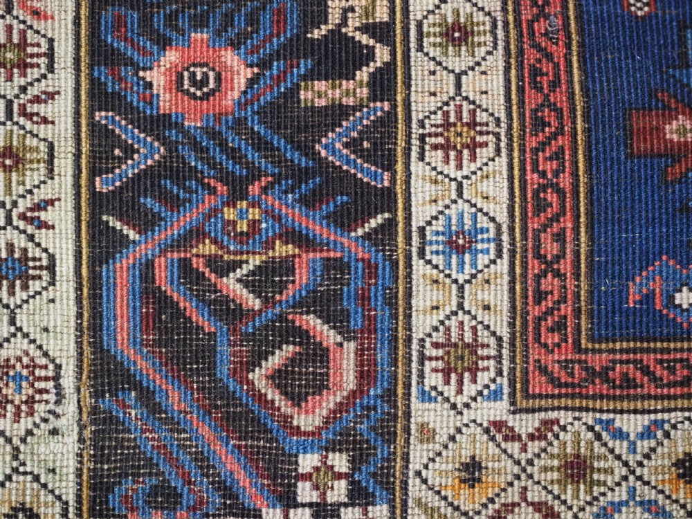 An antique hand-knotted Caucasian Alpan-Kuba runner rug featuring geometric diamond medallions in red and navy blue with detailed ivory borders. View XIII