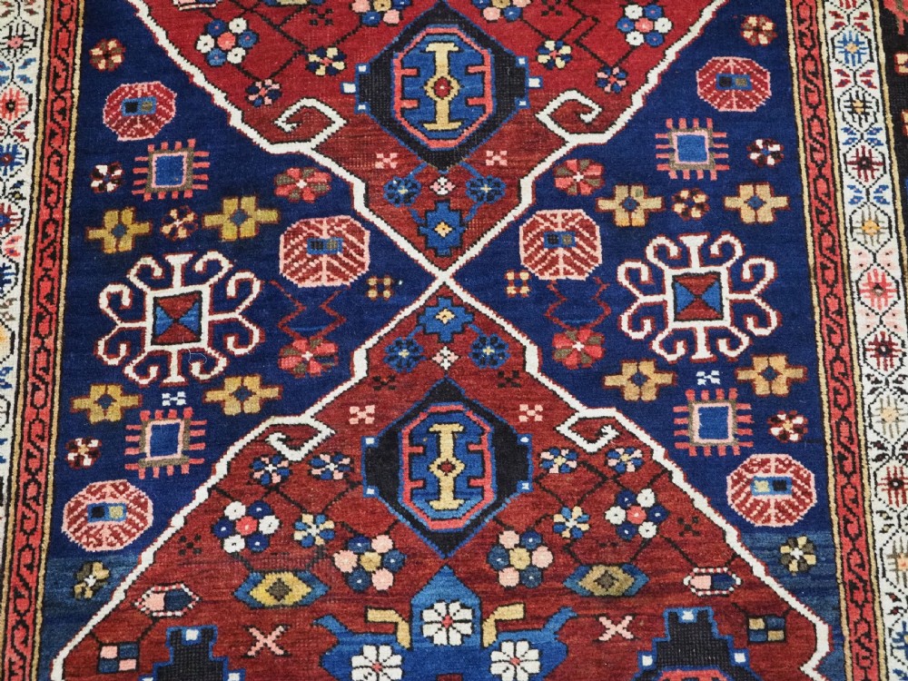 An antique hand-knotted Caucasian Alpan-Kuba runner rug featuring geometric diamond medallions in red and navy blue with detailed ivory borders. View XV