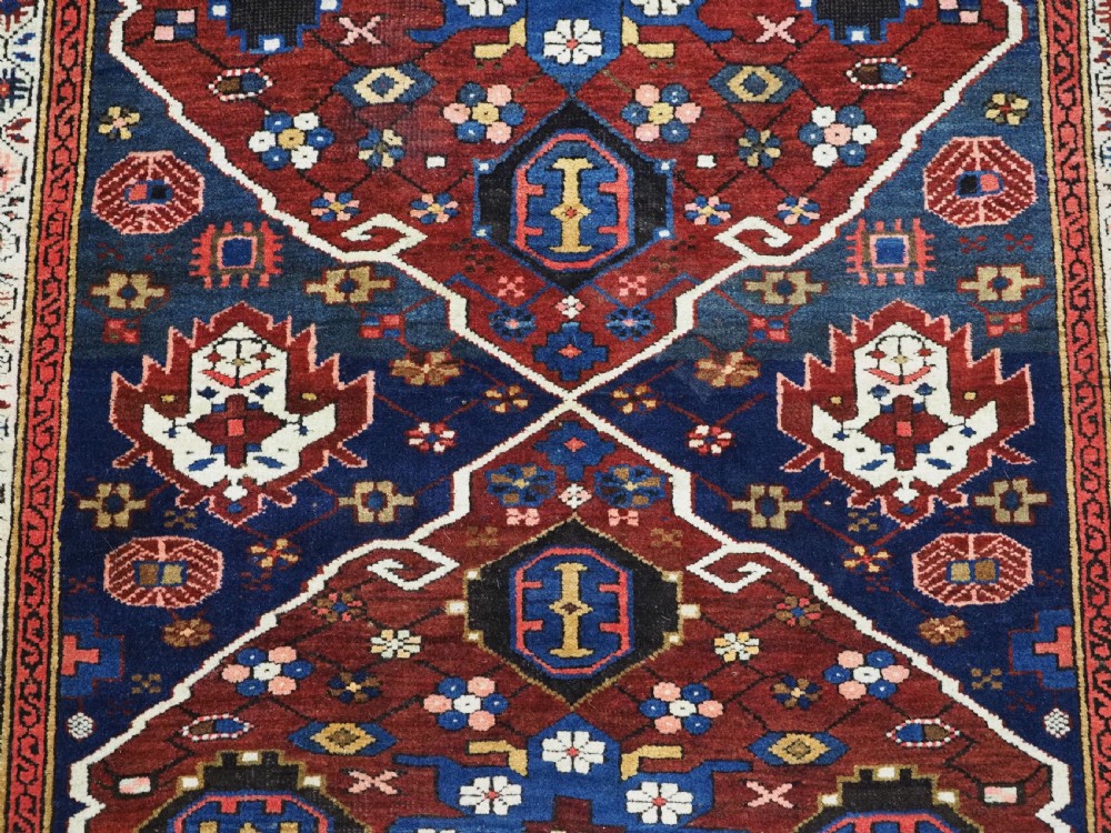 An antique hand-knotted Caucasian Alpan-Kuba runner rug featuring geometric diamond medallions in red and navy blue with detailed ivory borders. View XVI