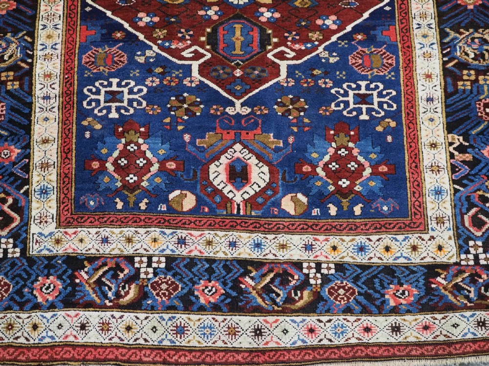 An antique hand-knotted Caucasian Alpan-Kuba runner rug featuring geometric diamond medallions in red and navy blue with detailed ivory borders. View XVII