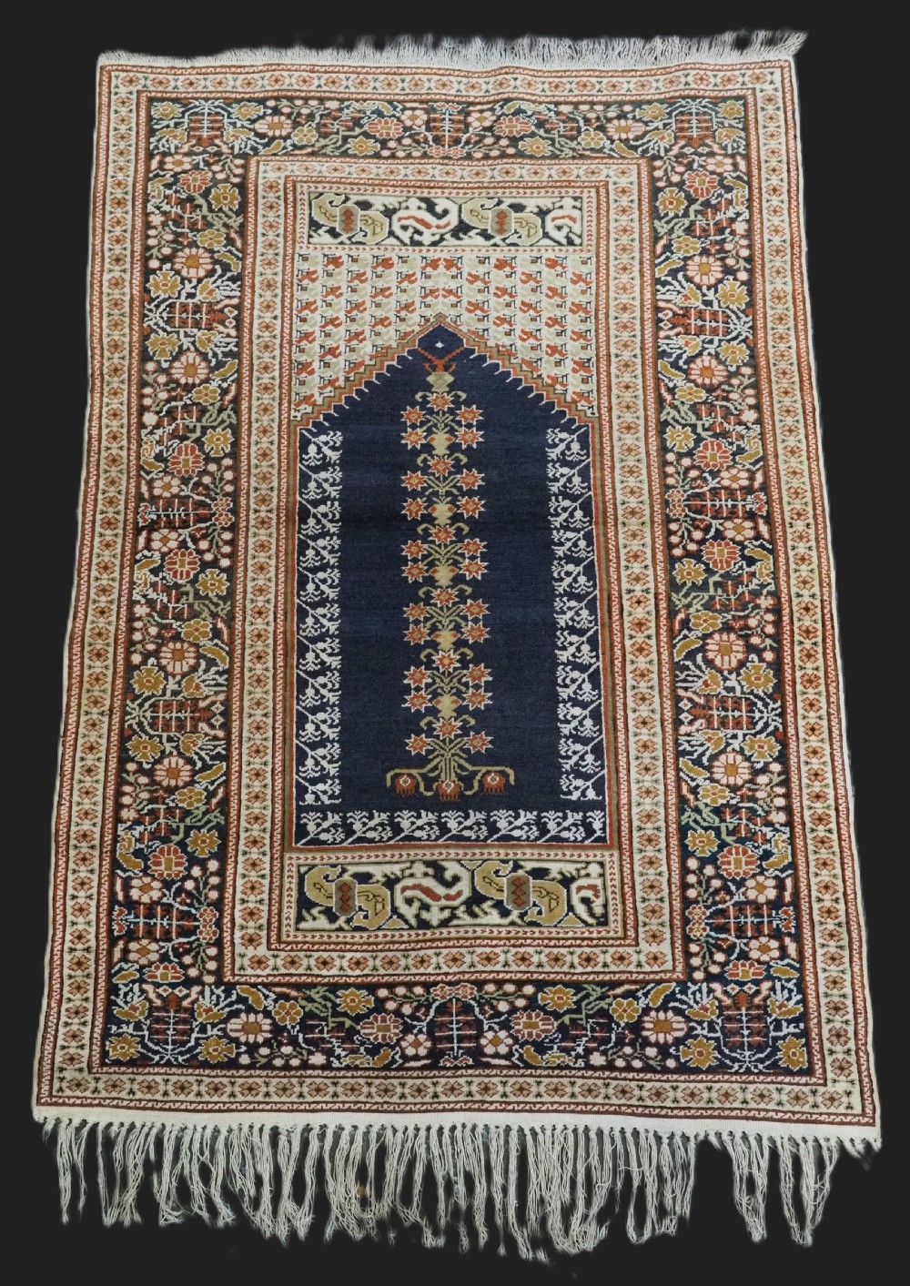 An antique Turkish Panderma hand-knotted wool prayer rug featuring a navy central niche with a floral motif surrounded by detailed ivory and rust geometric floral borders.