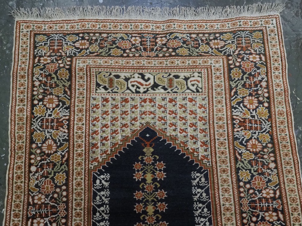An antique Turkish Panderma hand-knotted wool prayer rug featuring a navy central niche with a floral motif surrounded by detailed ivory and rust geometric floral borders. View III