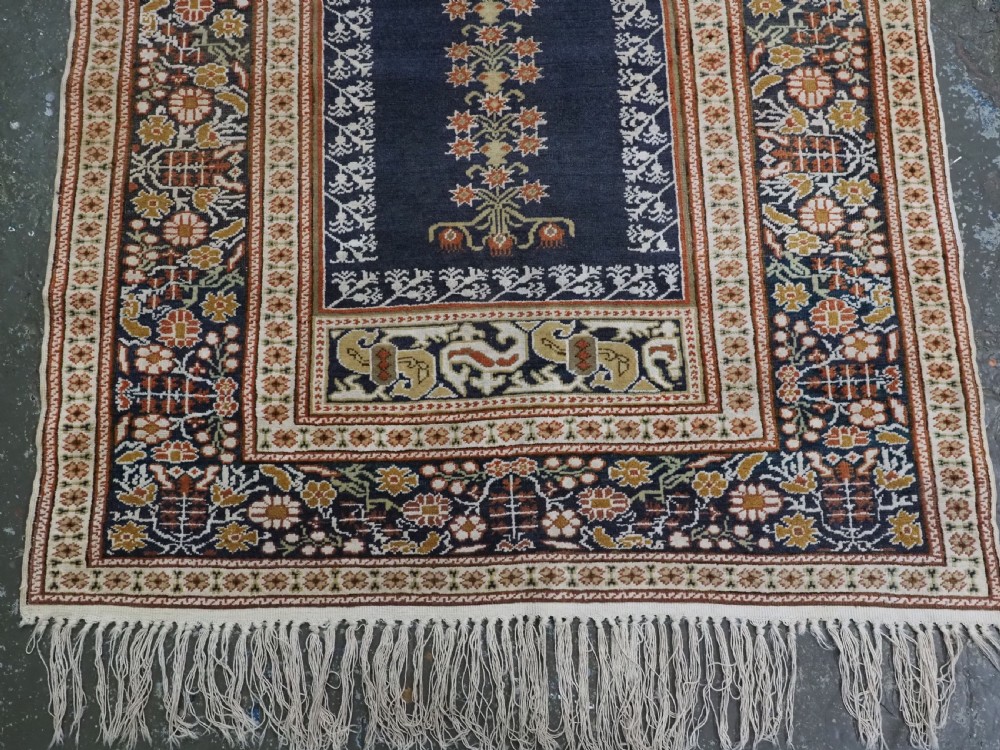 An antique Turkish Panderma hand-knotted wool prayer rug featuring a navy central niche with a floral motif surrounded by detailed ivory and rust geometric floral borders. View VI