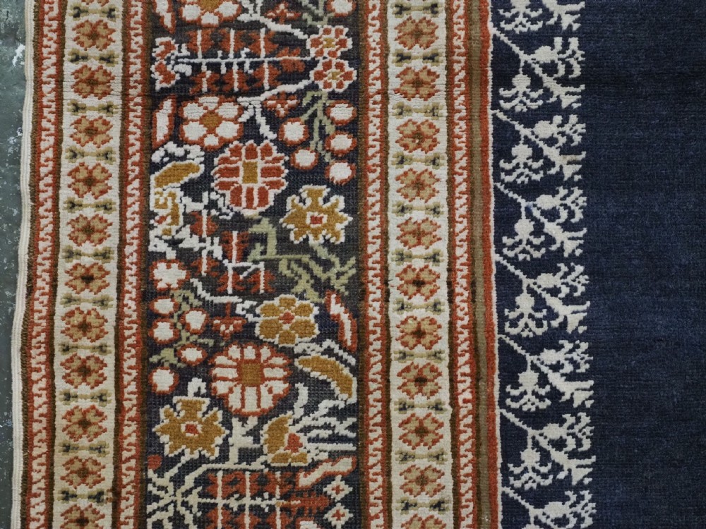 An antique Turkish Panderma hand-knotted wool prayer rug featuring a navy central niche with a floral motif surrounded by detailed ivory and rust geometric floral borders. View VII