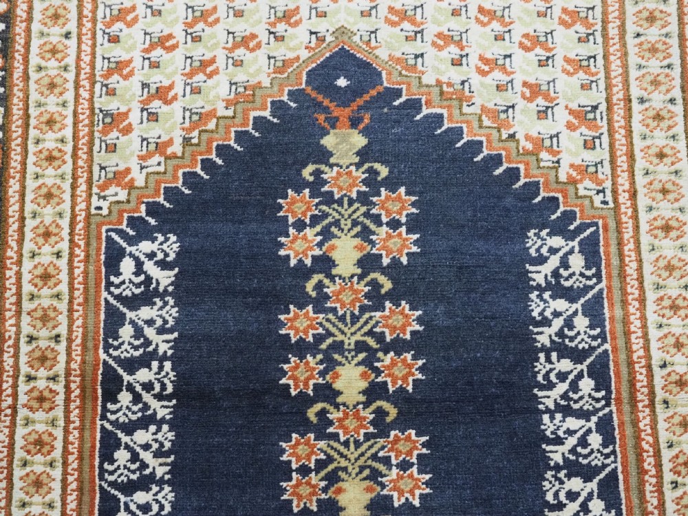 An antique Turkish Panderma hand-knotted wool prayer rug featuring a navy central niche with a floral motif surrounded by detailed ivory and rust geometric floral borders. View X