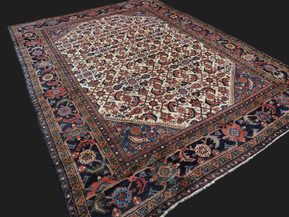 An antique hand-knotted Persian Mahal carpet featuring an ivory central field covered in geometric floral motifs surrounded by dark blue spandrels and a multi-banded border. View II