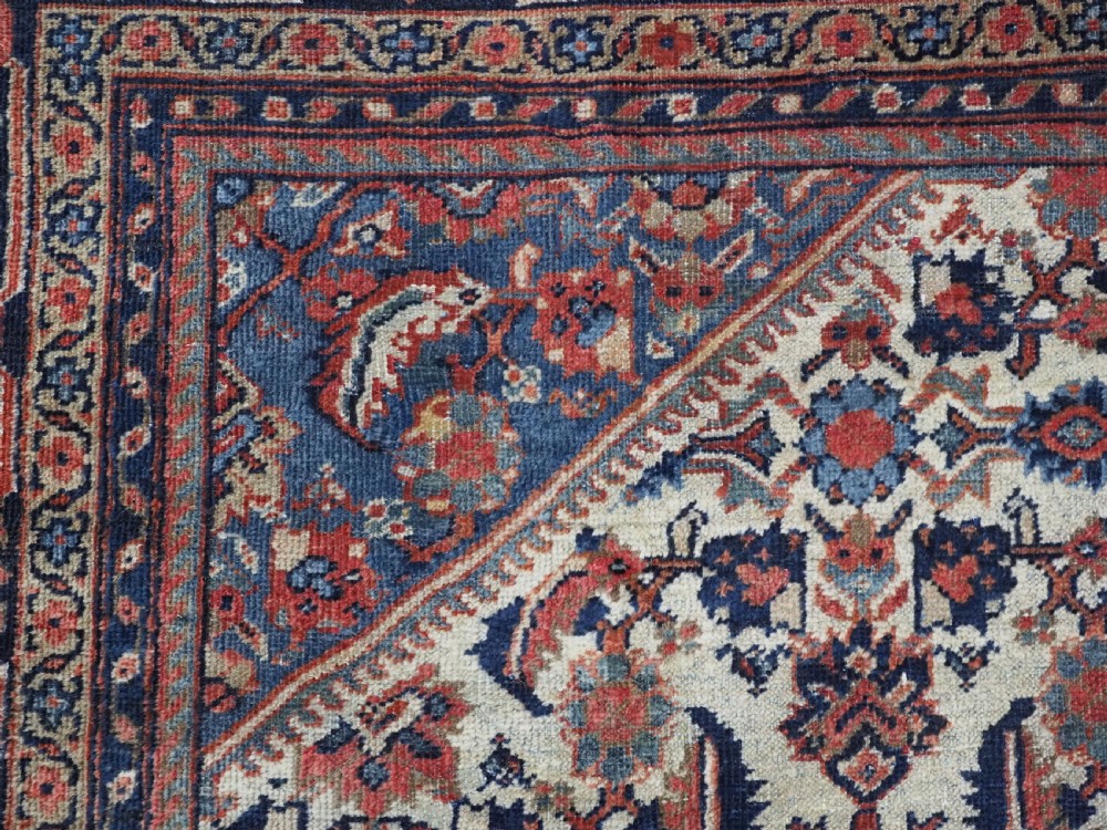 An antique hand-knotted Persian Mahal carpet featuring an ivory central field covered in geometric floral motifs surrounded by dark blue spandrels and a multi-banded border. View VIII