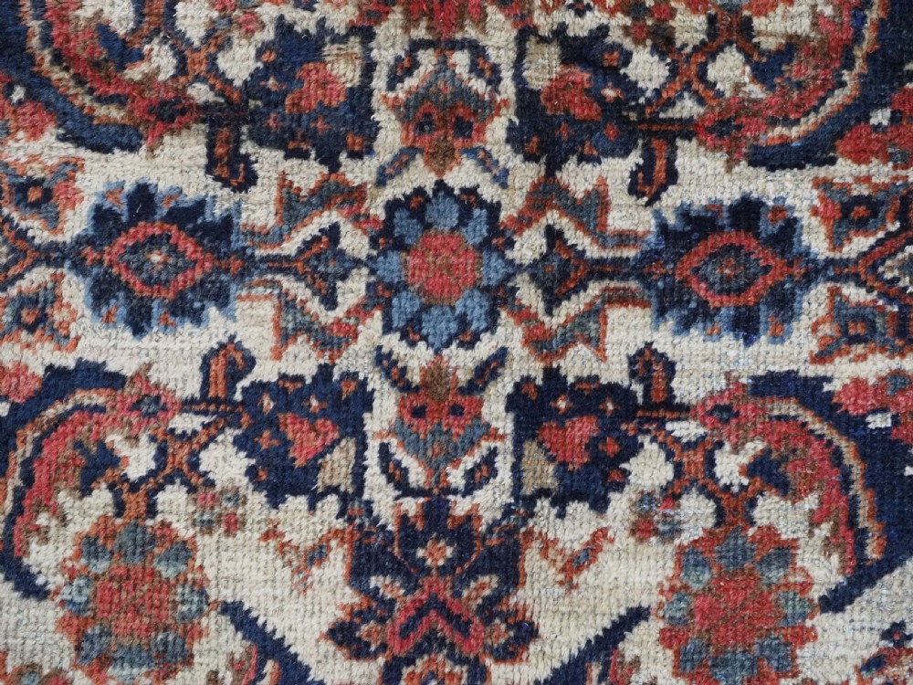 An antique hand-knotted Persian Mahal carpet featuring an ivory central field covered in geometric floral motifs surrounded by dark blue spandrels and a multi-banded border. View XII