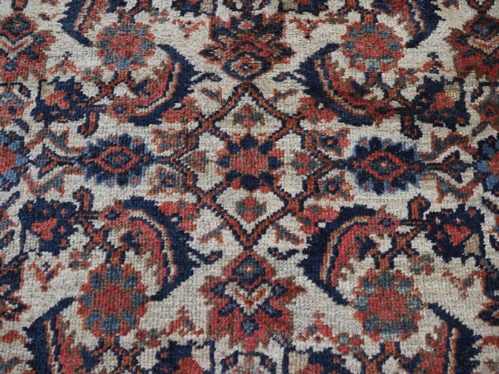 An antique hand-knotted Persian Mahal carpet featuring an ivory central field covered in geometric floral motifs surrounded by dark blue spandrels and a multi-banded border. View XIII