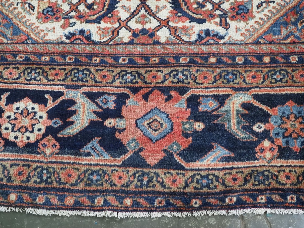 An antique hand-knotted Persian Mahal carpet featuring an ivory central field covered in geometric floral motifs surrounded by dark blue spandrels and a multi-banded border. View XIV
