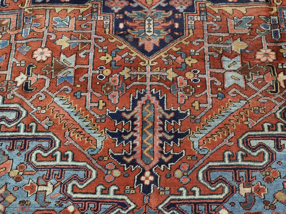 An antique hand-knotted wool Heriz carpet featuring a prominent central geometric star medallion in navy and sky blue surrounded by a terracotta field and stylized borders. View XIII
