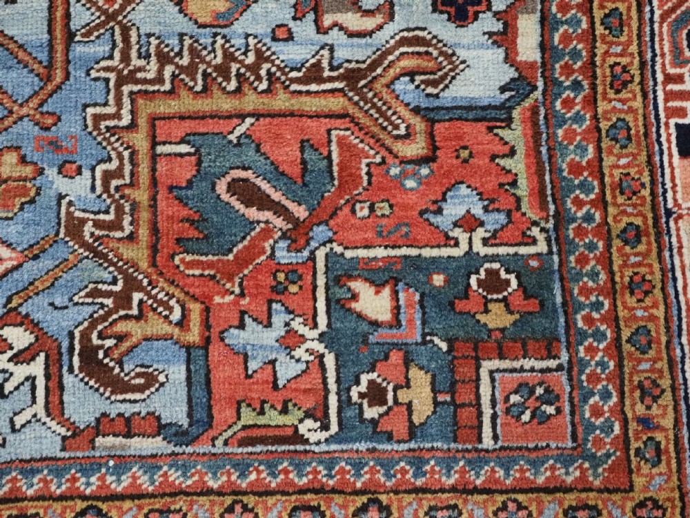 An antique hand-knotted wool Heriz carpet featuring a prominent central geometric star medallion in navy and sky blue surrounded by a terracotta field and stylized borders. View XVI