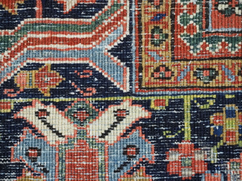 An antique hand-knotted wool Heriz carpet featuring a prominent central geometric star medallion in navy and sky blue surrounded by a terracotta field and stylized borders. View XIX