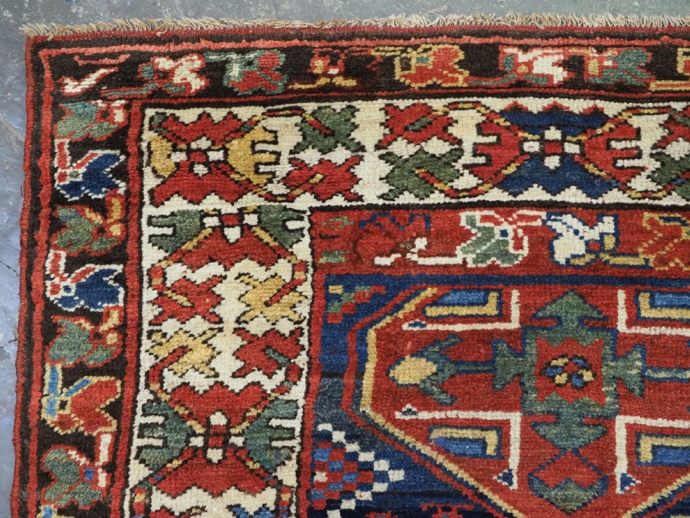An antique hand-knotted Caucasian wool runner rug featuring a sequence of geometric diamond medallions on an indigo blue field surrounded by patterned borders. View VIII