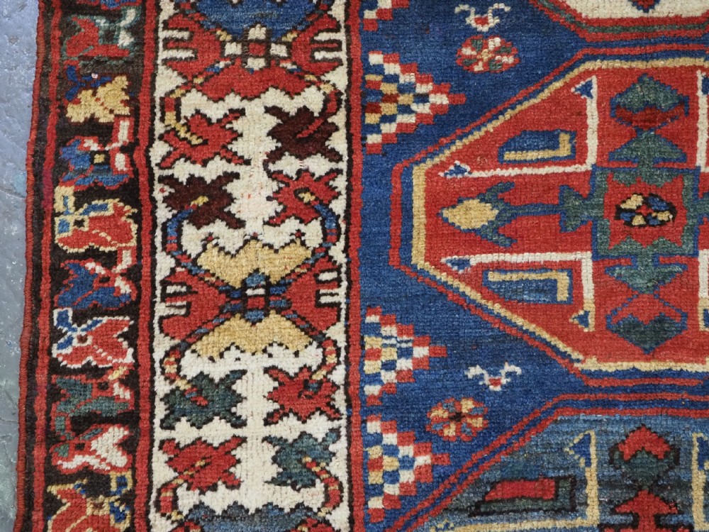 An antique hand-knotted Caucasian wool runner rug featuring a sequence of geometric diamond medallions on an indigo blue field surrounded by patterned borders. View IX