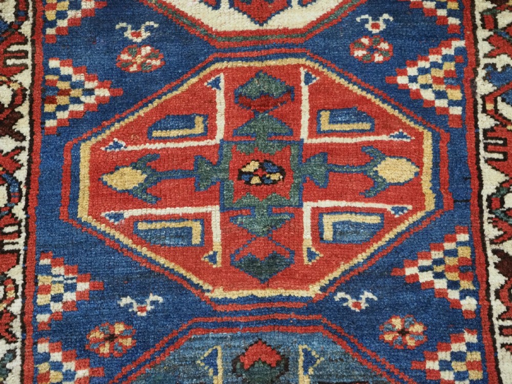 An antique hand-knotted Caucasian wool runner rug featuring a sequence of geometric diamond medallions on an indigo blue field surrounded by patterned borders. View XIII
