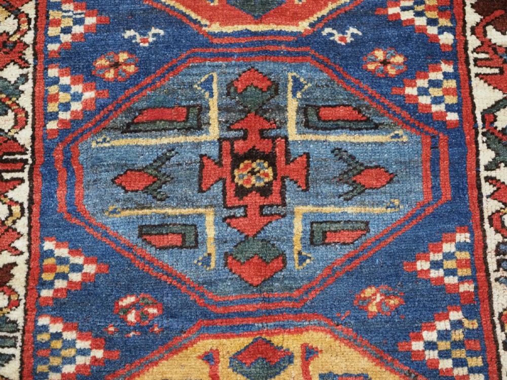 An antique hand-knotted Caucasian wool runner rug featuring a sequence of geometric diamond medallions on an indigo blue field surrounded by patterned borders. View XIV