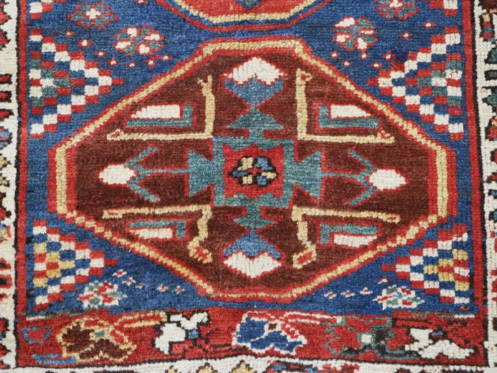 An antique hand-knotted Caucasian wool runner rug featuring a sequence of geometric diamond medallions on an indigo blue field surrounded by patterned borders. View XVI