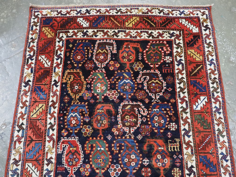 An antique Caucasian Gendje Kazak wool runner rug featuring repeating colourful boteh motifs on a dark navy field framed by geometric red and white borders. View III