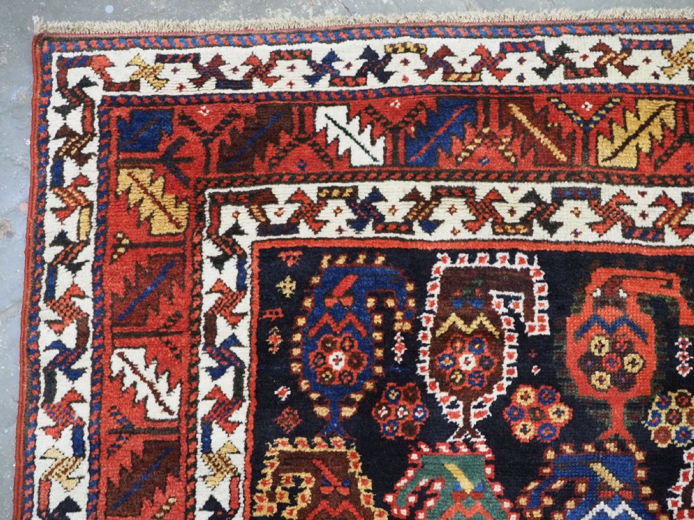 An antique Caucasian Gendje Kazak wool runner rug featuring repeating colourful boteh motifs on a dark navy field framed by geometric red and white borders. View VIII