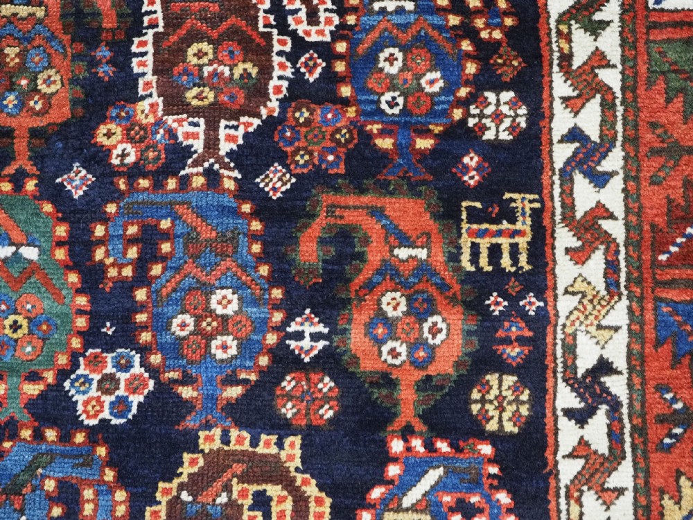 An antique Caucasian Gendje Kazak wool runner rug featuring repeating colourful boteh motifs on a dark navy field framed by geometric red and white borders. View XI