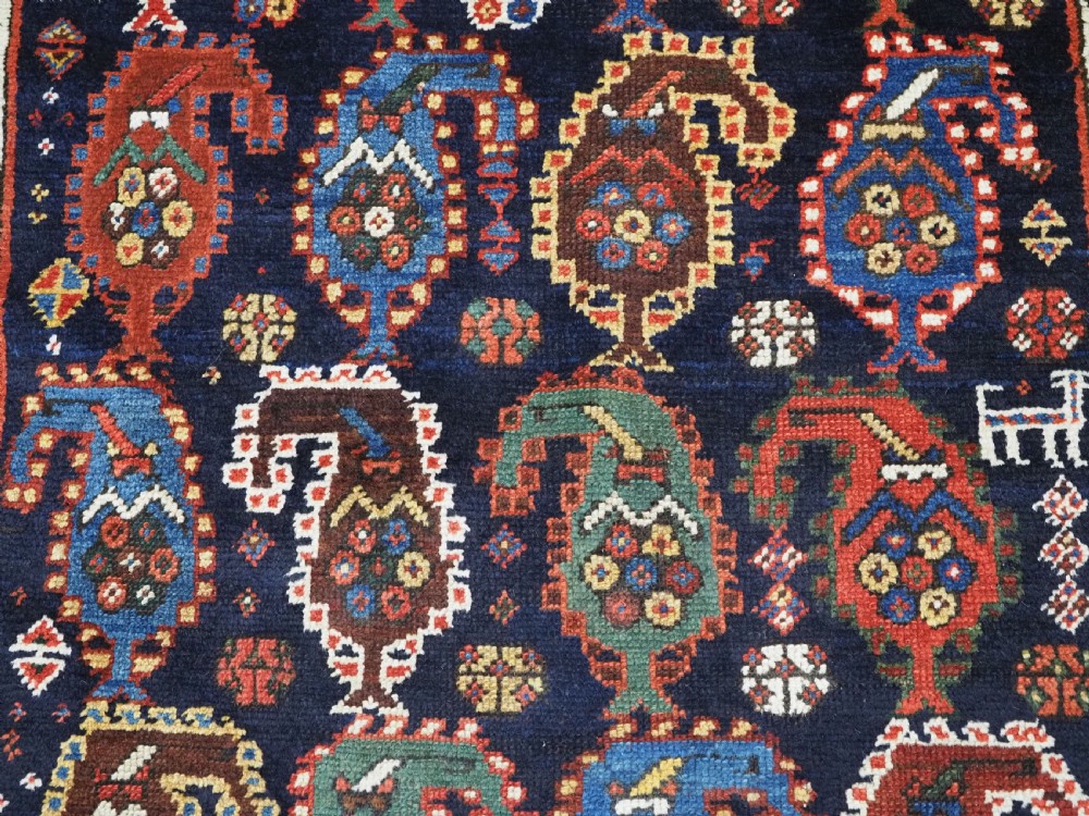 An antique Caucasian Gendje Kazak wool runner rug featuring repeating colourful boteh motifs on a dark navy field framed by geometric red and white borders. View XII