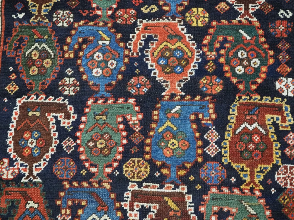 An antique Caucasian Gendje Kazak wool runner rug featuring repeating colourful boteh motifs on a dark navy field framed by geometric red and white borders. View XIII