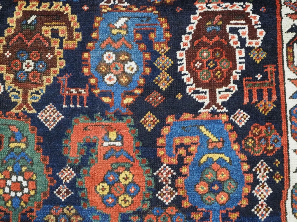An antique Caucasian Gendje Kazak wool runner rug featuring repeating colourful boteh motifs on a dark navy field framed by geometric red and white borders. View XIV