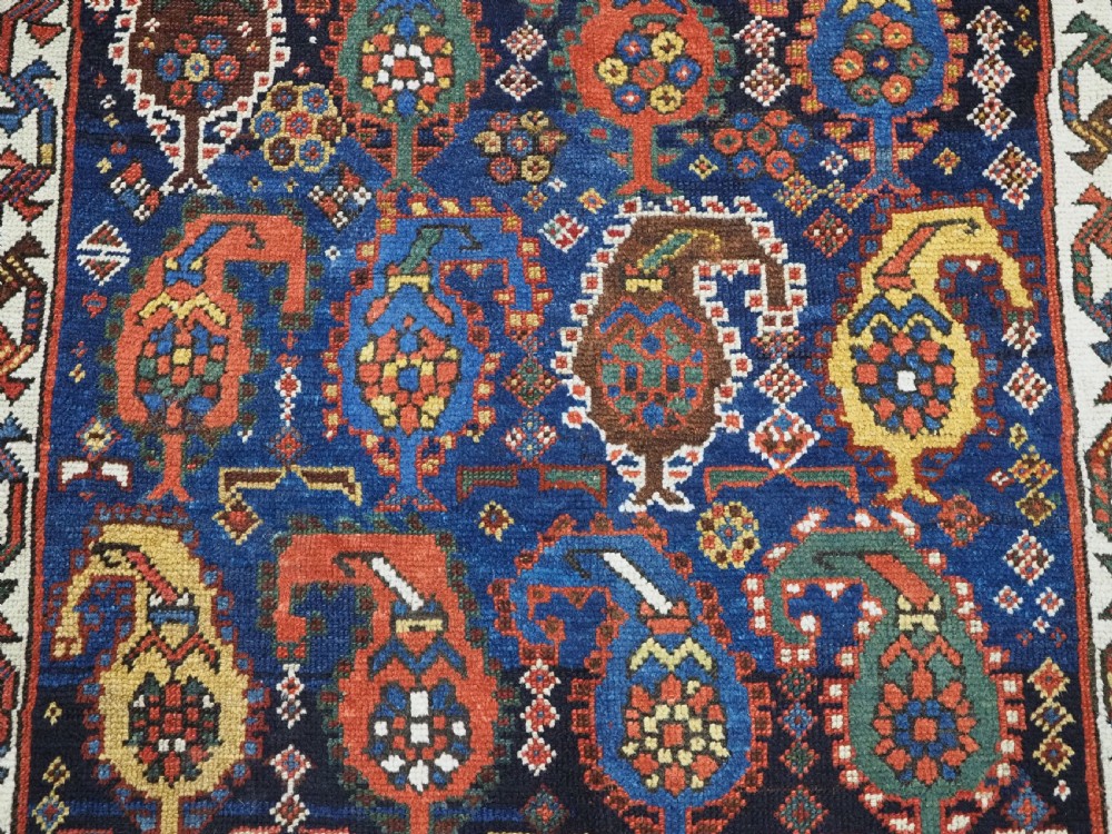 An antique Caucasian Gendje Kazak wool runner rug featuring repeating colourful boteh motifs on a dark navy field framed by geometric red and white borders. View XV