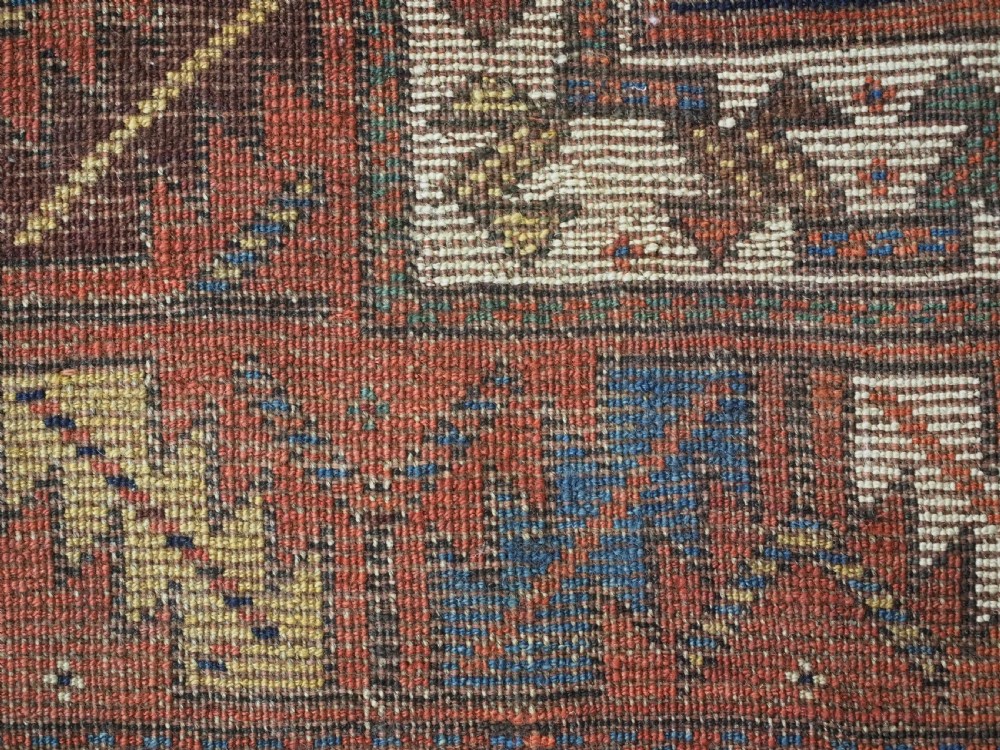 An antique Caucasian Gendje Kazak wool runner rug featuring repeating colourful boteh motifs on a dark navy field framed by geometric red and white borders. View XVII