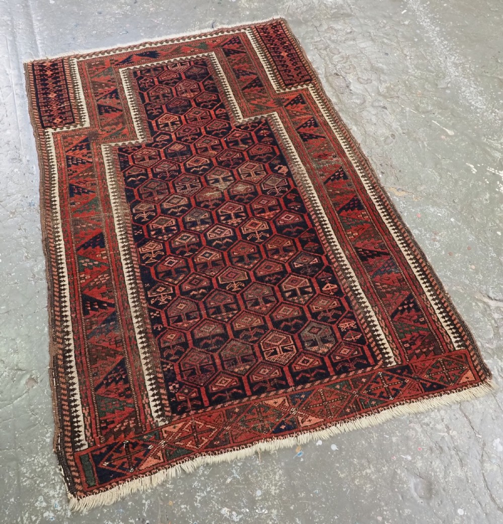 A hand-knotted wool prayer rug with a stepped mihrab niche, repeating geometric tree motifs, and a dark indigo blue and terracotta red palette. View II