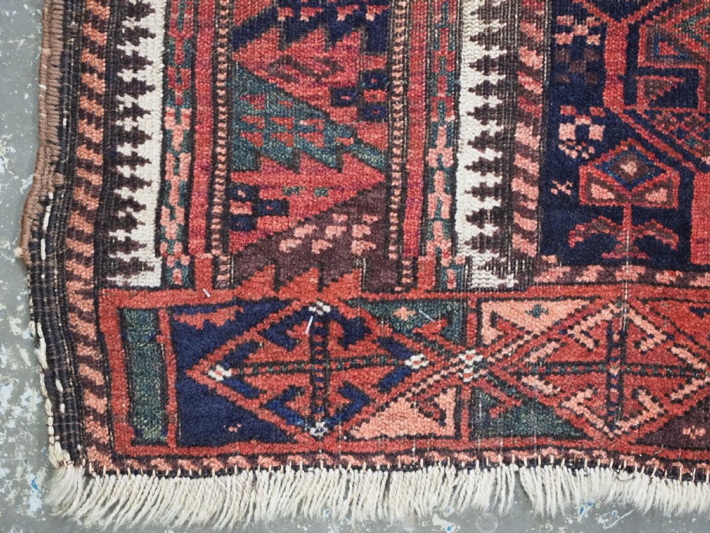 A hand-knotted wool prayer rug with a stepped mihrab niche, repeating geometric tree motifs, and a dark indigo blue and terracotta red palette. View XII