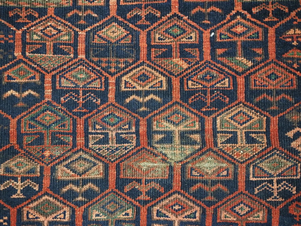 A hand-knotted wool prayer rug with a stepped mihrab niche, repeating geometric tree motifs, and a dark indigo blue and terracotta red palette. View XIII