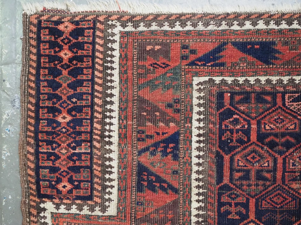 A hand-knotted wool prayer rug with a stepped mihrab niche, repeating geometric tree motifs, and a dark indigo blue and terracotta red palette. View XVI