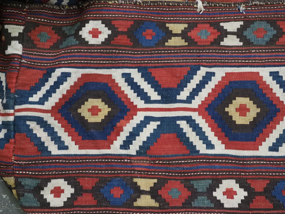 An antique hand-woven rectangular Caucasian mafrash storage bag decorated with red, blue, cream, and yellow geometric soumak patterns. View II