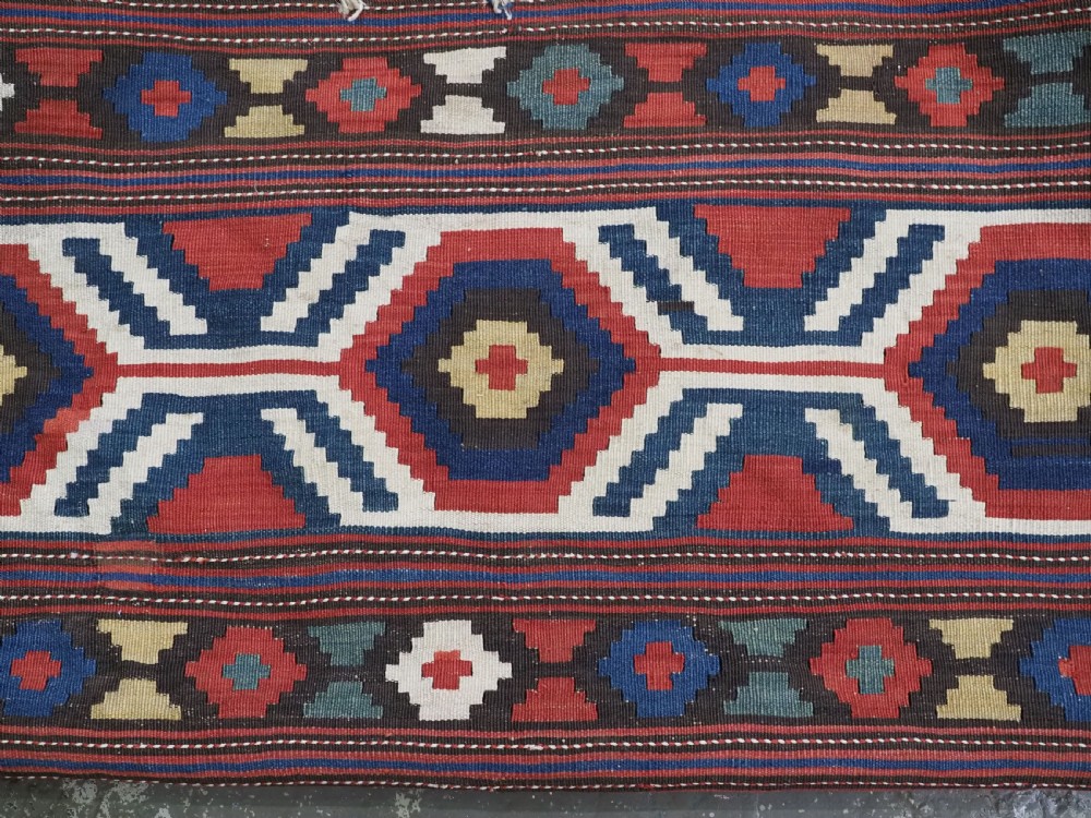 An antique hand-woven rectangular Caucasian mafrash storage bag decorated with red, blue, cream, and yellow geometric soumak patterns. View III