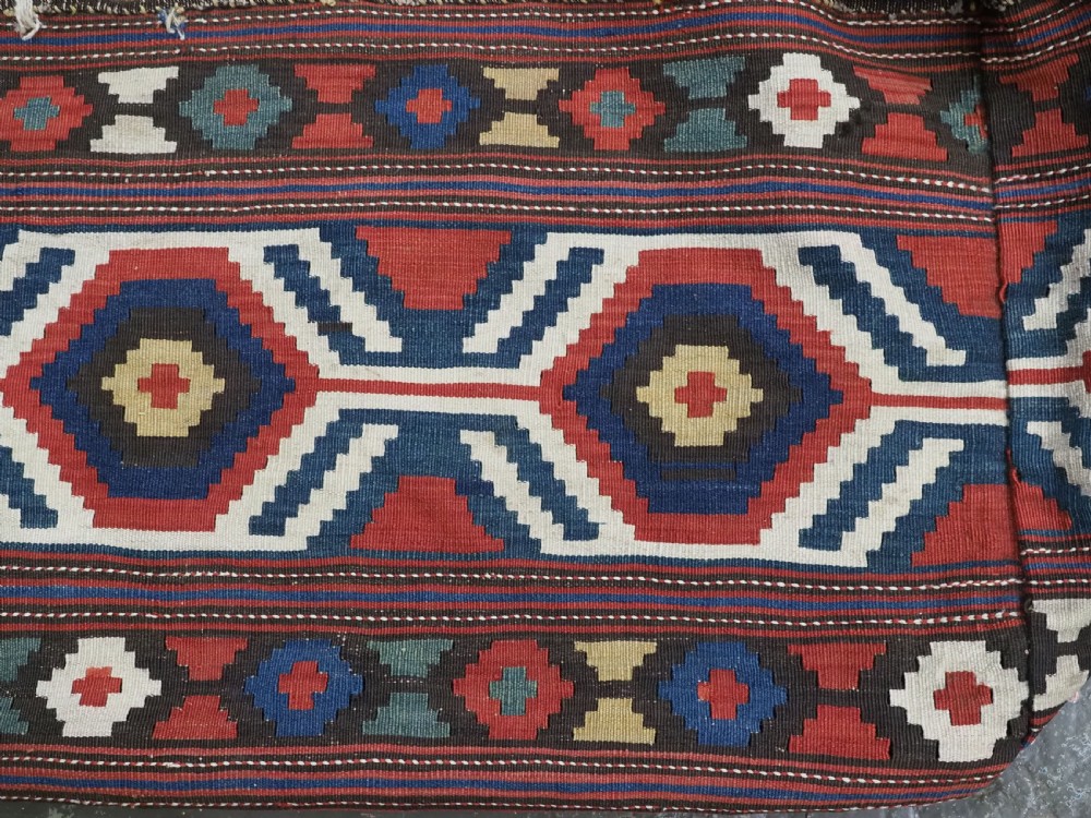 An antique hand-woven rectangular Caucasian mafrash storage bag decorated with red, blue, cream, and yellow geometric soumak patterns. View V