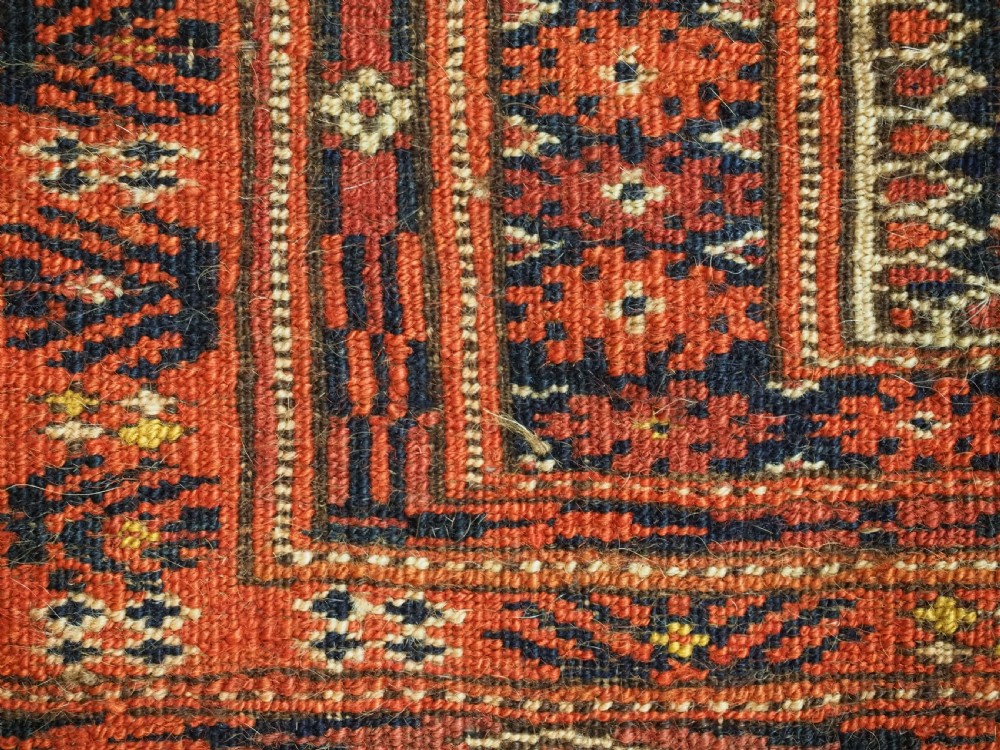 An elongated antique Turkmen torba textile displaying geometric diamond medallion motifs in deep red, dark navy, and cream wool with fringed bottom edge. View X