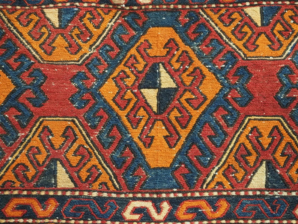An antique South Caucasian mafrash storage bag featuring vibrant terracotta, navy blue, and cream geometric diamond patterns flat-woven in wool. View V