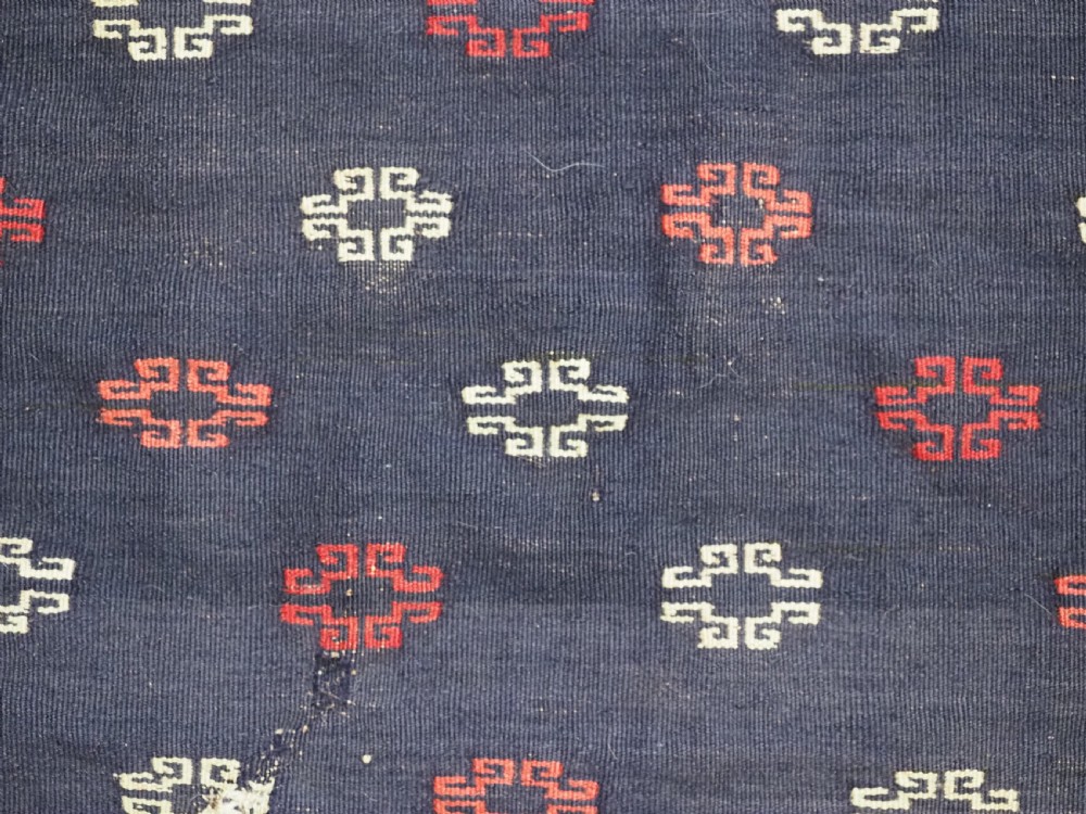 A rectangular antique Baluch sofreh flatweave textile featuring an indigo blue centre with small geometric motifs framed by serrated red and dark blue borders. View VII