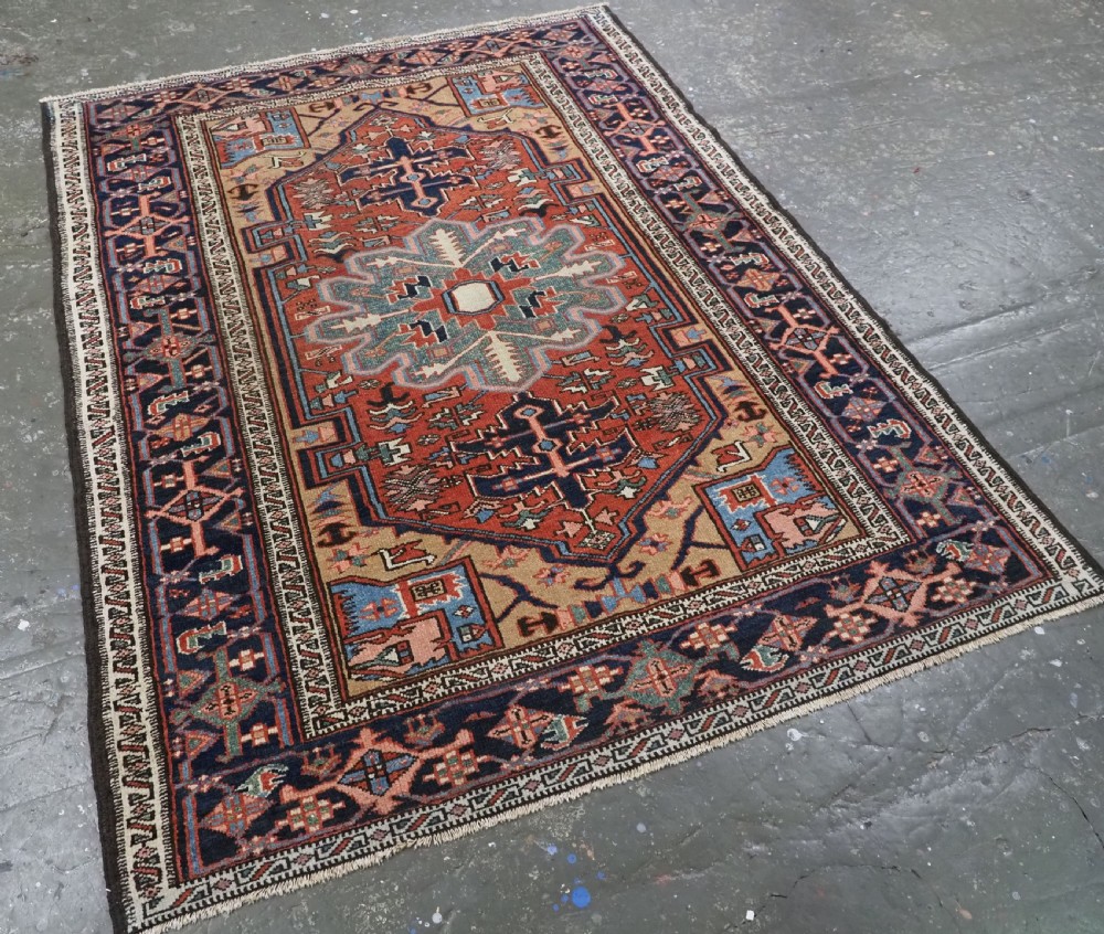 An antique hand-knotted Persian Heriz rug featuring a central starburst medallion in teal, terracotta, and cream on a patterned ground with a multi-band geometric border. View II