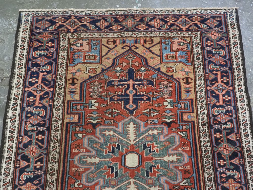 An antique hand-knotted Persian Heriz rug featuring a central starburst medallion in teal, terracotta, and cream on a patterned ground with a multi-band geometric border. View III