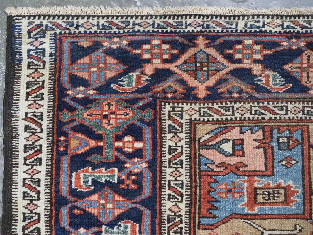 An antique hand-knotted Persian Heriz rug featuring a central starburst medallion in teal, terracotta, and cream on a patterned ground with a multi-band geometric border. View VI